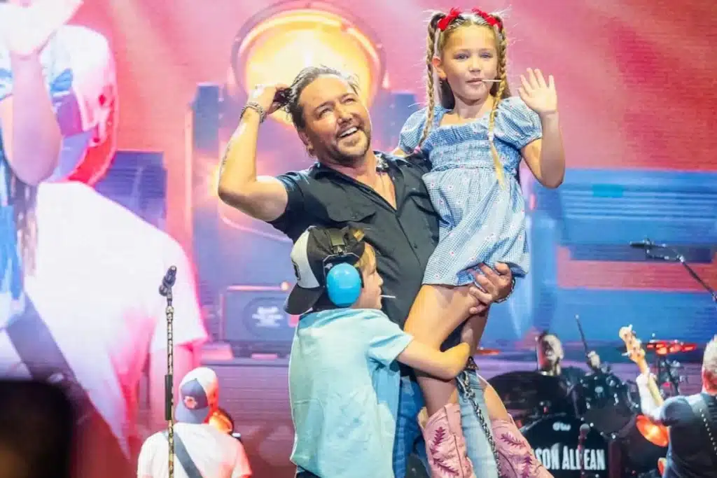 Jason Aldean shocked everyone in Salt Lake City when his two youngest children, Memphis and Navy, suddenly joined him onstage during the final minutes of his concert. The two kids, just 6 and 7 years old, waved shyly at the crowd as Aldean knelt to hug them in front of thousands of fans. Brittany Aldean was seen watching from the sidelines, but her facial expression caught in fan videos has sparked even more speculation.