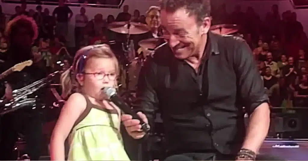 “How old are you, sweetheart?” Bruce Springsteen asked it softly as he leaned down from the stage, eyes fixed on a tiny girl near the front row — no taller than his guitar, dancing like the music belonged only to her. The noise, the lights, the decades of rock history behind him all faded in that instant. Her parents answered, barely holding it together: “She’s four.” Bruce smiled, paused, then turned to the crowd with a glint of emotion in his eyes and said, “Well folks… looks like the E Street Band just got its youngest member tonight.” The arena erupted, but not in the usual way. This cheer carried warmth, surprise, and something close to tears. The concert transformed into something more than a show — a quiet passing of the torch wrapped in laughter and awe. It wasn’t about the encore. It wasn’t about the setlist. It was about a little girl dancing without fear — and a rock legend reminding everyone that music doesn’t belong to history… it belongs to whoever feels it first.