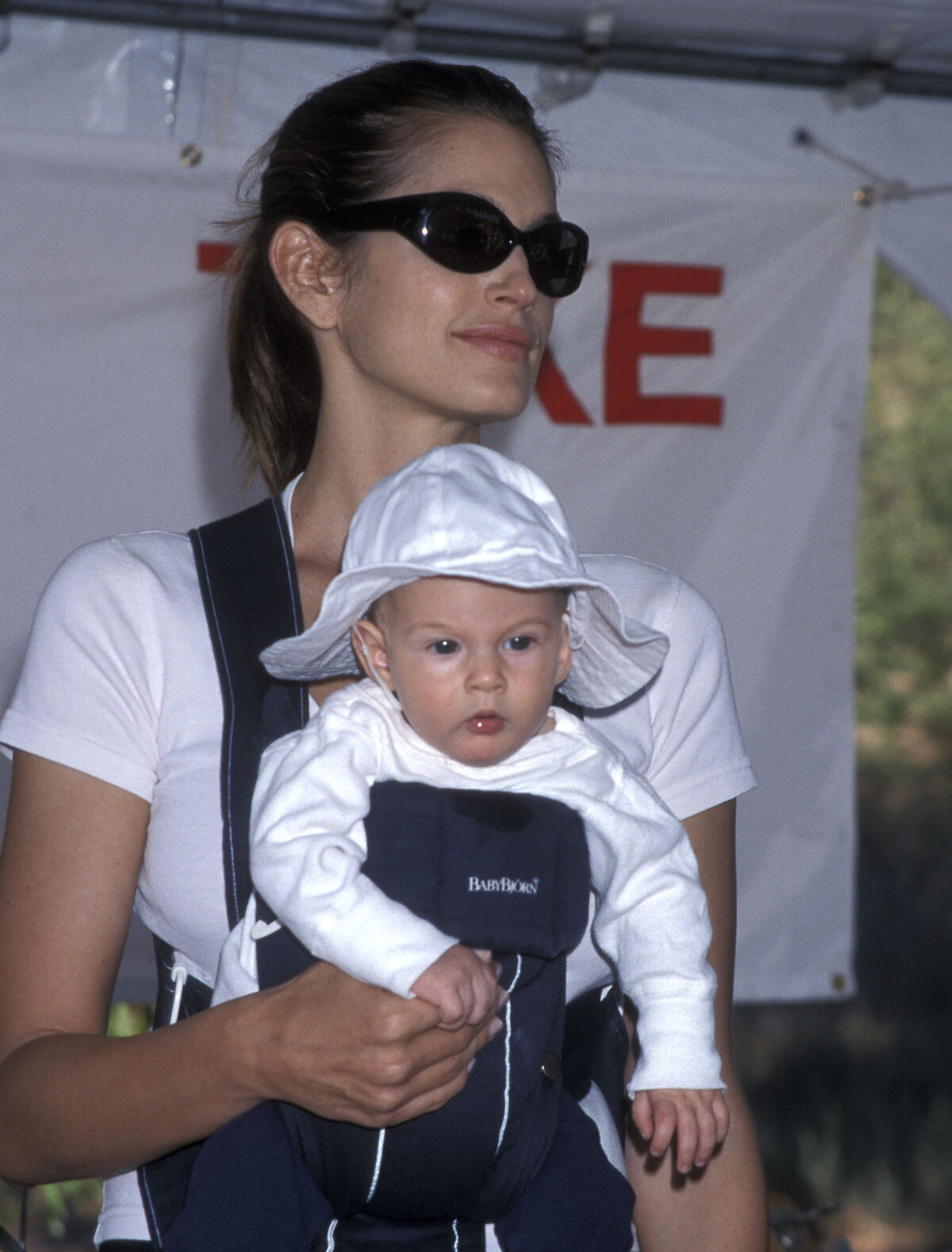 Supermodel Cindy Crawford carried her infant son, Presley Gerber, in a front baby carrier while attending a charity run for breast cancer research at Paramount Ranch in Agoura Hills, California, on October 9, 1999, keeping cool under dark sunglasses as her baby sported a white bucket hat. | Source: